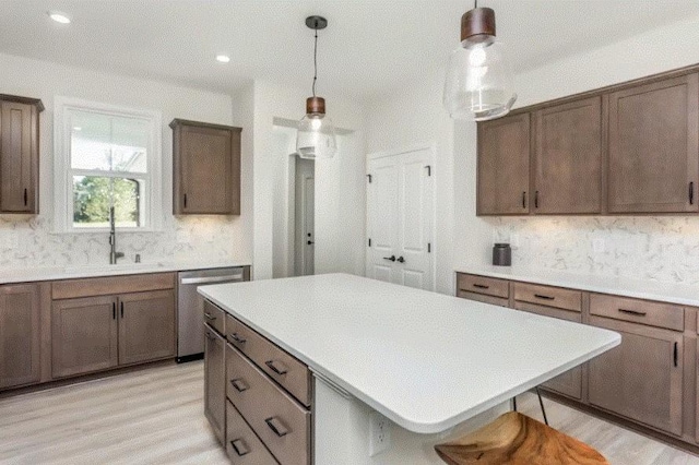 kitchen featuring stainless steel dishwasher, a breakfast bar, pendant lighting, and light hardwood / wood-style floors