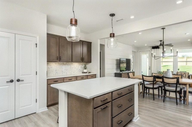 kitchen with ceiling fan, a center island, light hardwood / wood-style flooring, pendant lighting, and dark brown cabinets