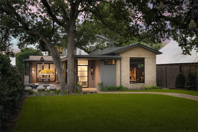 view of front facade featuring a fireplace, a yard, and a patio