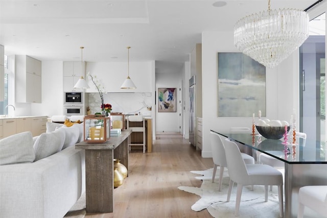 dining room with a notable chandelier, sink, and light hardwood / wood-style flooring