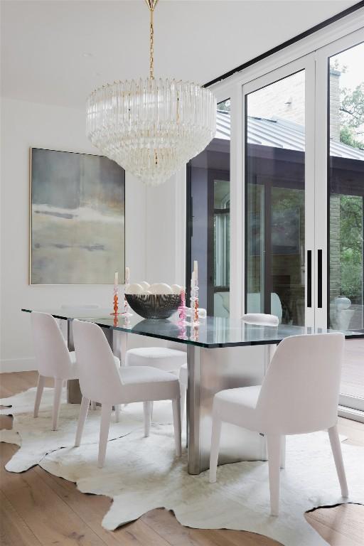 dining space with light wood-type flooring and a notable chandelier