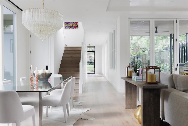 dining space with ceiling fan with notable chandelier and light hardwood / wood-style floors