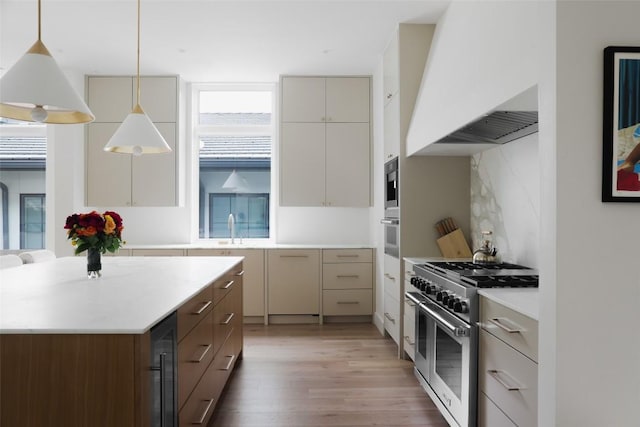 kitchen featuring decorative backsplash, appliances with stainless steel finishes, premium range hood, pendant lighting, and hardwood / wood-style floors