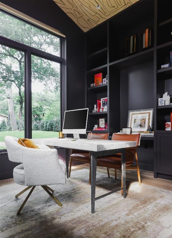 office area featuring hardwood / wood-style floors, built in shelves, and vaulted ceiling