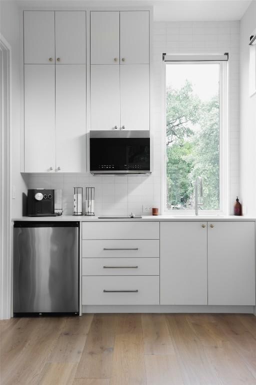 kitchen with stainless steel appliances, white cabinetry, a healthy amount of sunlight, and light hardwood / wood-style floors