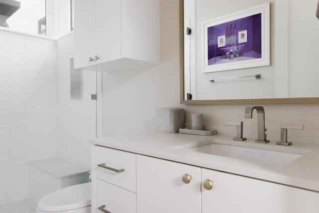 bathroom featuring tiled shower, vanity, and toilet