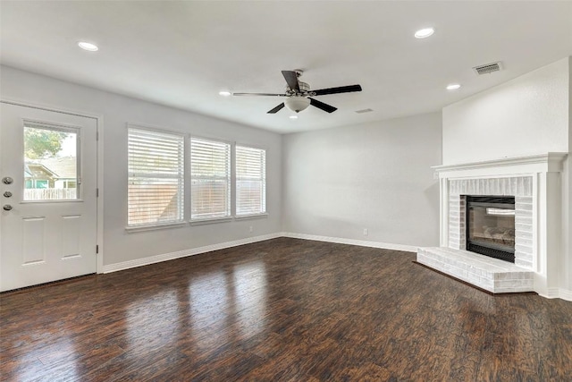 unfurnished living room featuring a brick fireplace, ceiling fan, and dark wood-type flooring