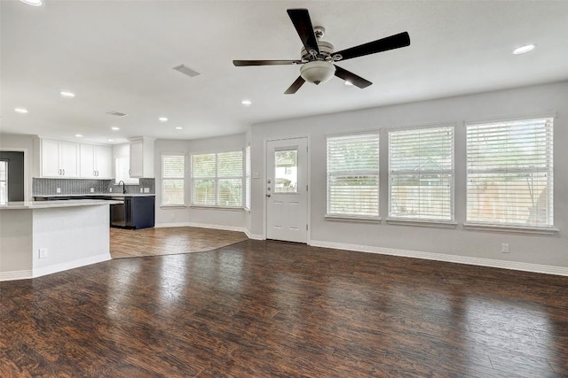 unfurnished living room with dark hardwood / wood-style floors, ceiling fan, and sink