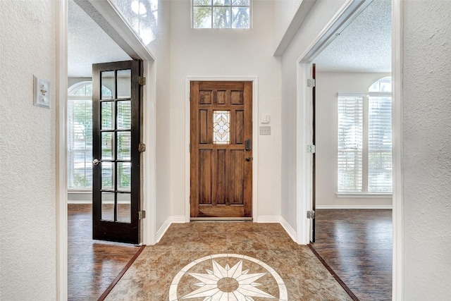 entrance foyer with french doors, a textured ceiling, and hardwood / wood-style flooring