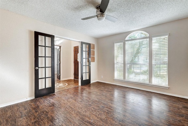 empty room with ceiling fan, french doors, dark wood-type flooring, and a textured ceiling