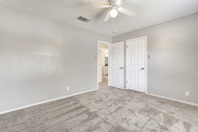 unfurnished bedroom with ceiling fan, light colored carpet, and a textured ceiling