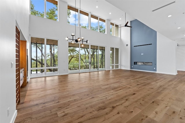 2206 Trail Of The Madrones, Austin, TX 78746 - unfurnished living room with high vaulted ceiling, ceiling fan with notable chandelier, and hardwood / wood-style flooring