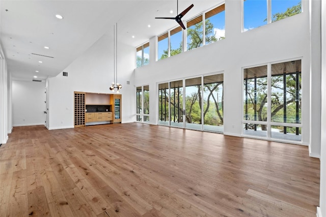 2206 Trail Of The Madrones, Austin, TX 78746 - unfurnished living room featuring a high ceiling, light hardwood / wood-style floors, and plenty of natural light