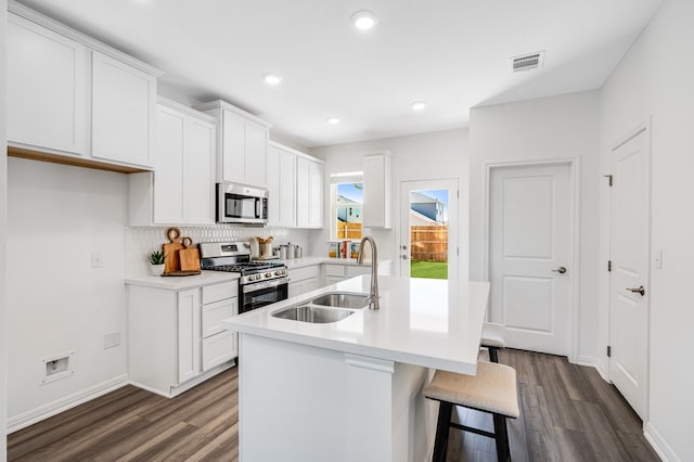 kitchen featuring appliances with stainless steel finishes, dark wood-style flooring, a sink, and decorative backsplash