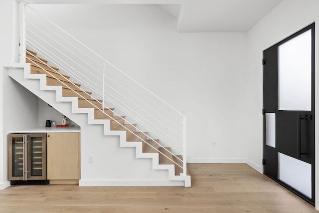 stairs featuring bar, wood-type flooring, and wine cooler