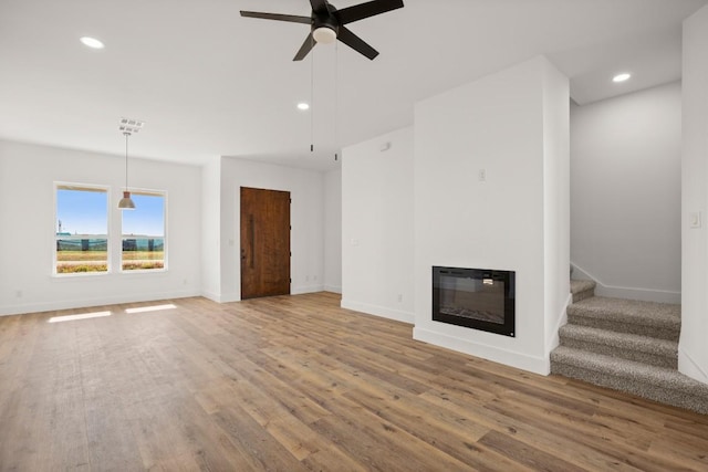 unfurnished living room featuring ceiling fan and hardwood / wood-style floors