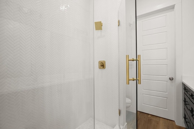 bathroom with hardwood / wood-style floors, vanity, toilet, and an enclosed shower