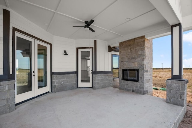 view of patio with an outdoor stone fireplace, ceiling fan, and french doors