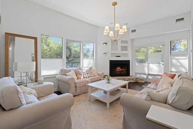 living room with built in shelves, light wood-type flooring, and a chandelier