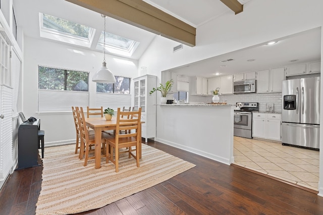 dining room featuring wood-type flooring, a healthy amount of sunlight, and vaulted ceiling with skylight