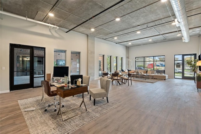 office area with a towering ceiling and hardwood / wood-style flooring