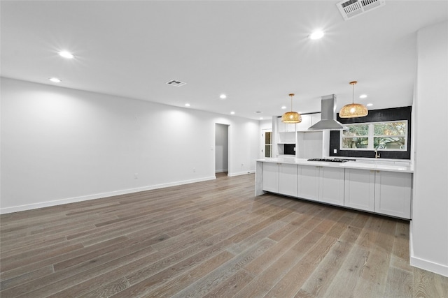 kitchen featuring hanging light fixtures, light hardwood / wood-style flooring, black gas stovetop, island range hood, and white cabinets