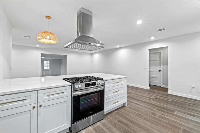 kitchen featuring white cabinetry, stainless steel range with gas cooktop, decorative light fixtures, and wall chimney range hood