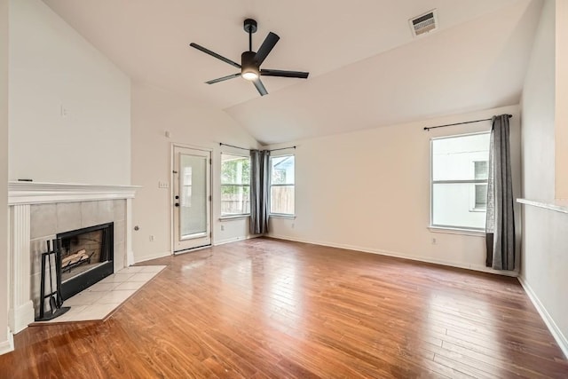 unfurnished living room with ceiling fan, light hardwood / wood-style floors, a tile fireplace, and vaulted ceiling