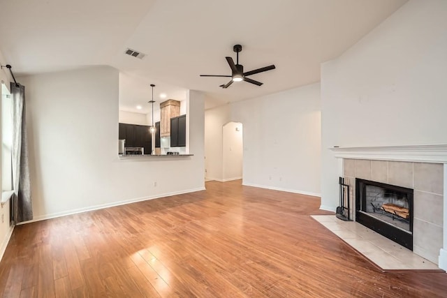 unfurnished living room with ceiling fan, a fireplace, and light hardwood / wood-style floors