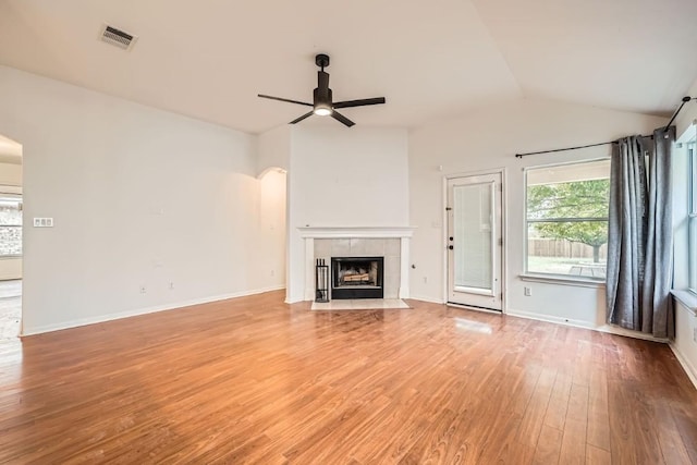 unfurnished living room with hardwood / wood-style floors, ceiling fan, a tile fireplace, and vaulted ceiling