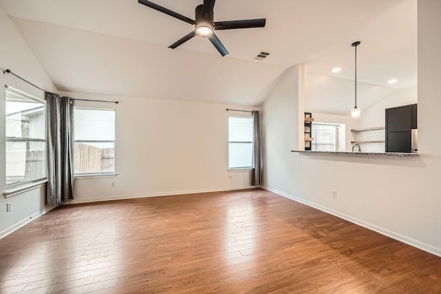 unfurnished living room featuring a wealth of natural light, ceiling fan, dark wood-type flooring, and vaulted ceiling