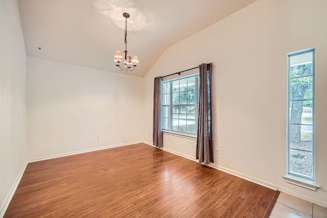 spare room with hardwood / wood-style flooring, lofted ceiling, and a notable chandelier