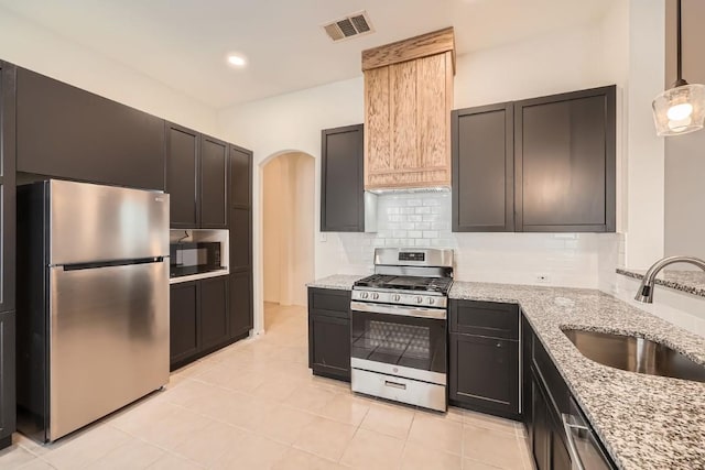 kitchen with pendant lighting, sink, light stone countertops, tasteful backsplash, and stainless steel appliances