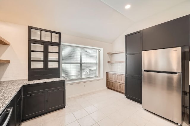 kitchen featuring light stone counters, stainless steel appliances, and vaulted ceiling