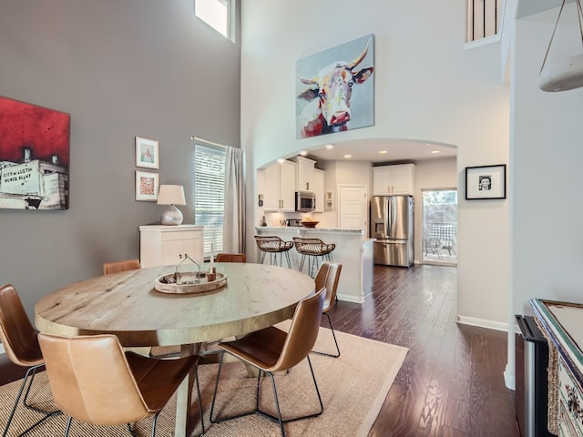 dining space featuring dark hardwood / wood-style flooring and a high ceiling