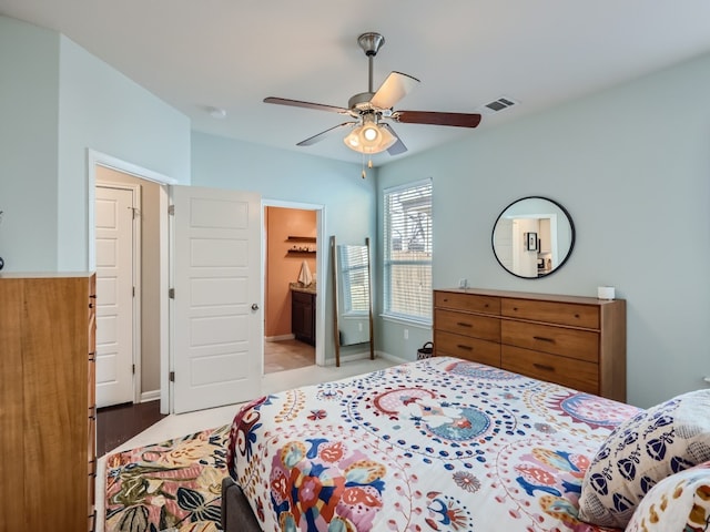 bedroom featuring connected bathroom, light hardwood / wood-style floors, and ceiling fan