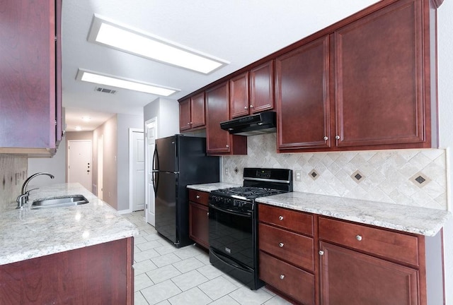 kitchen with sink, backsplash, light stone counters, and black appliances