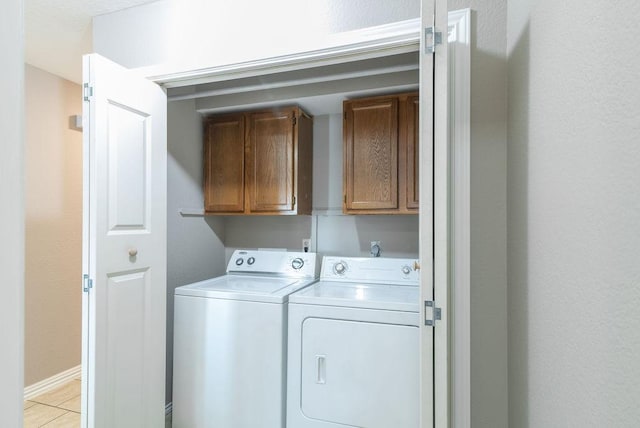 laundry area with light tile patterned flooring, cabinets, and independent washer and dryer