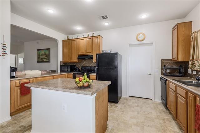 kitchen with black appliances, a center island, sink, and tasteful backsplash