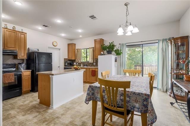 kitchen with pendant lighting, a center island, black appliances, tasteful backsplash, and a notable chandelier