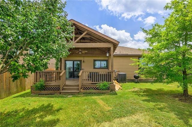 rear view of property featuring central air condition unit, a deck, ceiling fan, and a lawn