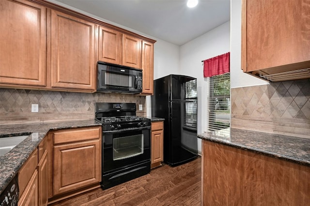 kitchen featuring decorative backsplash, dark stone counters, dark wood-type flooring, and black appliances