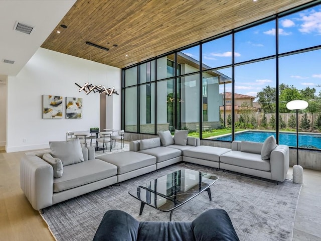 living room with hardwood / wood-style floors, wood ceiling, a wall of windows, and a high ceiling