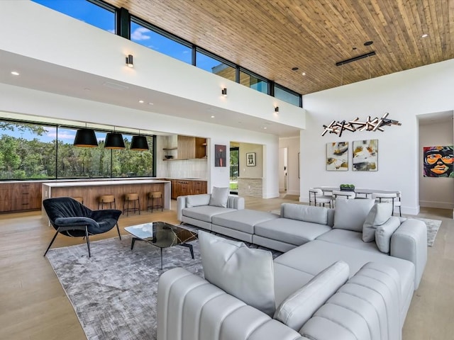 living room with light hardwood / wood-style floors, wooden ceiling, and a towering ceiling