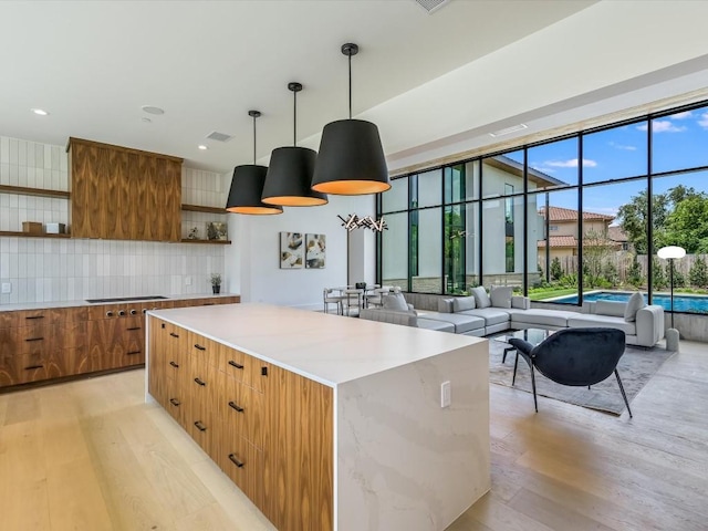 kitchen featuring light hardwood / wood-style floors, a kitchen island, hanging light fixtures, and tasteful backsplash