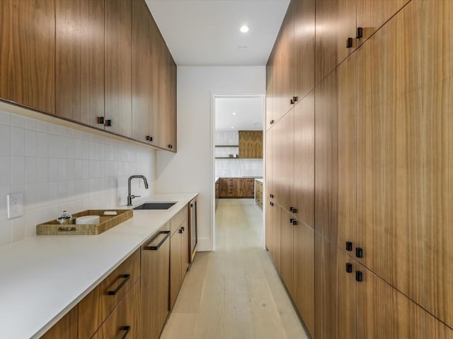 kitchen with decorative backsplash, light wood-type flooring, and sink