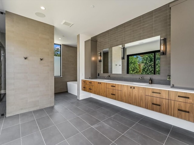 bathroom featuring tile patterned floors, vanity, a bathtub, and tile walls