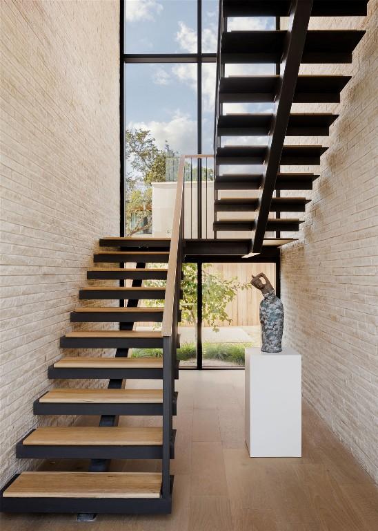 stairs with a wall of windows, brick wall, and a towering ceiling