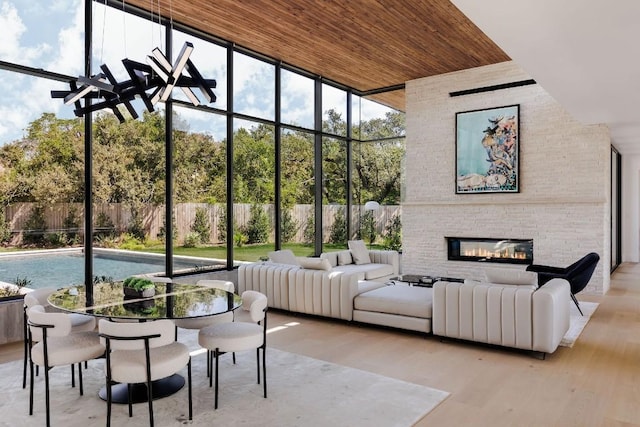 sunroom featuring a stone fireplace and wood ceiling