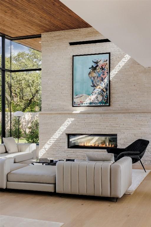 unfurnished living room featuring wooden ceiling, a large fireplace, expansive windows, and light hardwood / wood-style floors